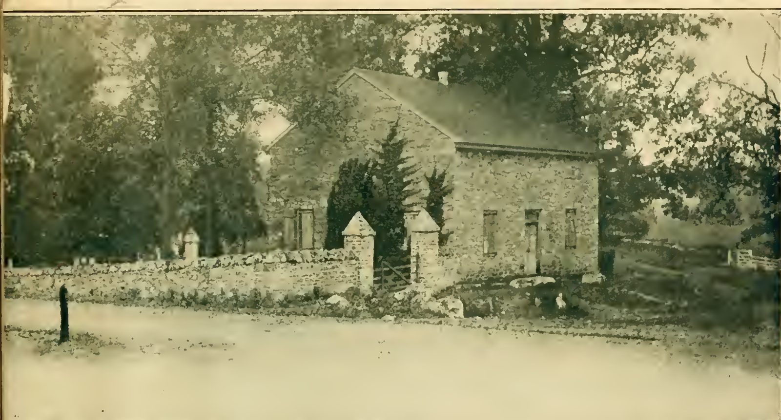 A black-and-white photograph of the Old Chapel, a small stone church with a gabled roof and arched windows, set among trees.